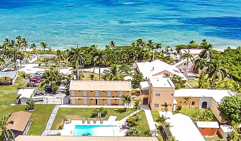 Vue aérienne d'un complexe hôtelier tropical avec piscine et végétation luxuriante.