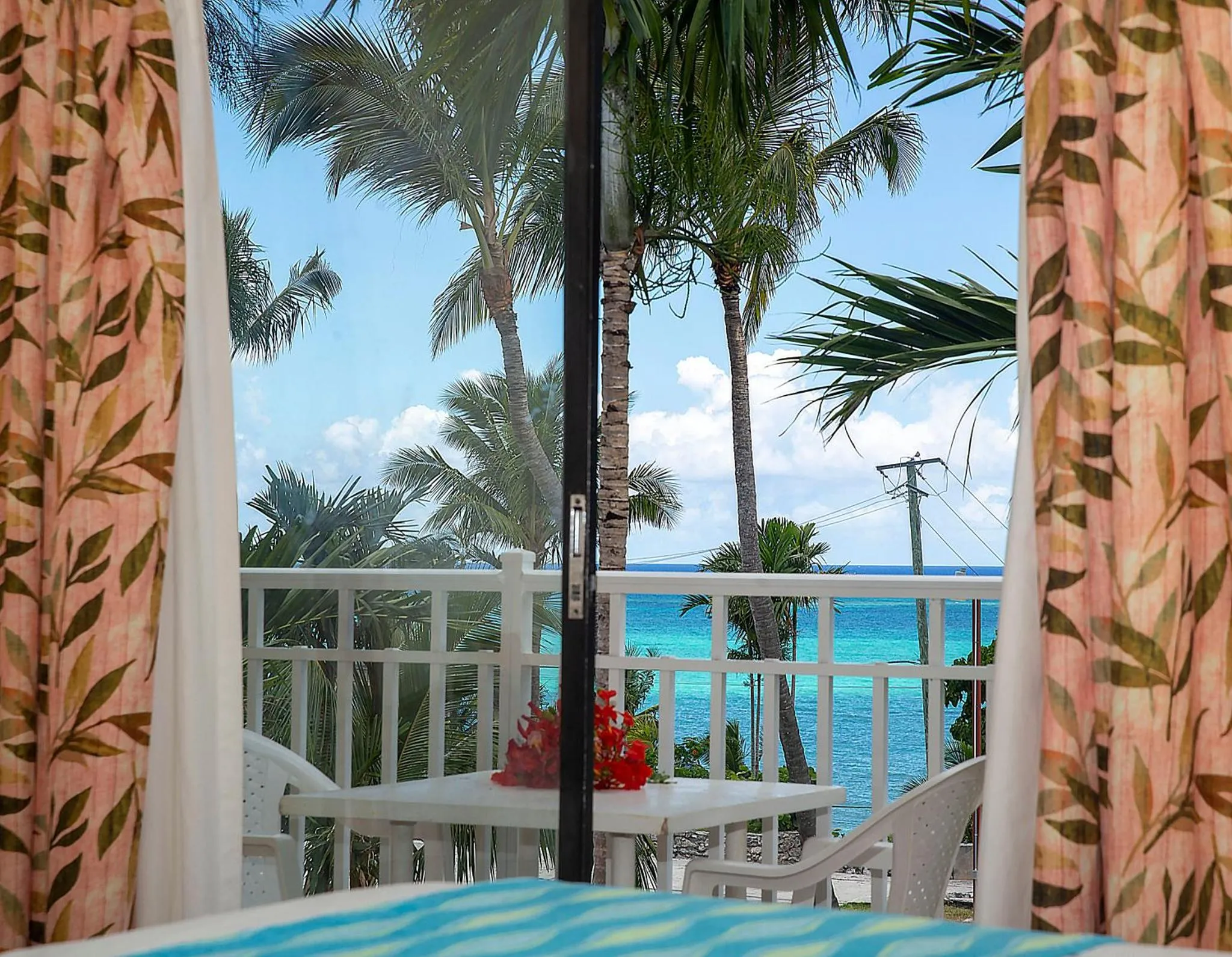 Vue sur la mer et la végétation tropicale depuis une terrasse.