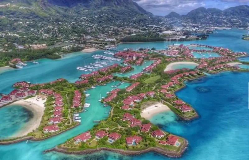 Vue aérienne d'un complexe hôtelier insulaire entouré d'une eau turquoise.