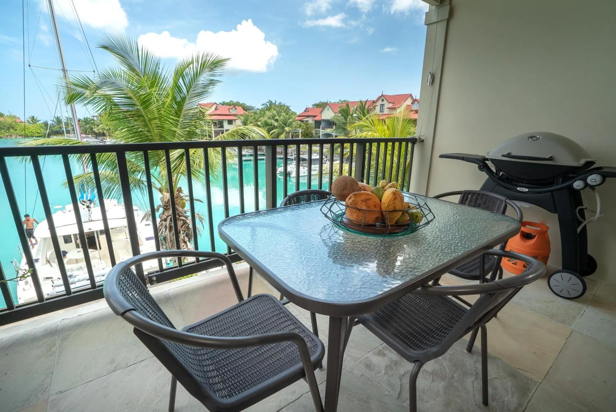 Table et chaises sur une terrasse avec vue sur la mer et la végétation.