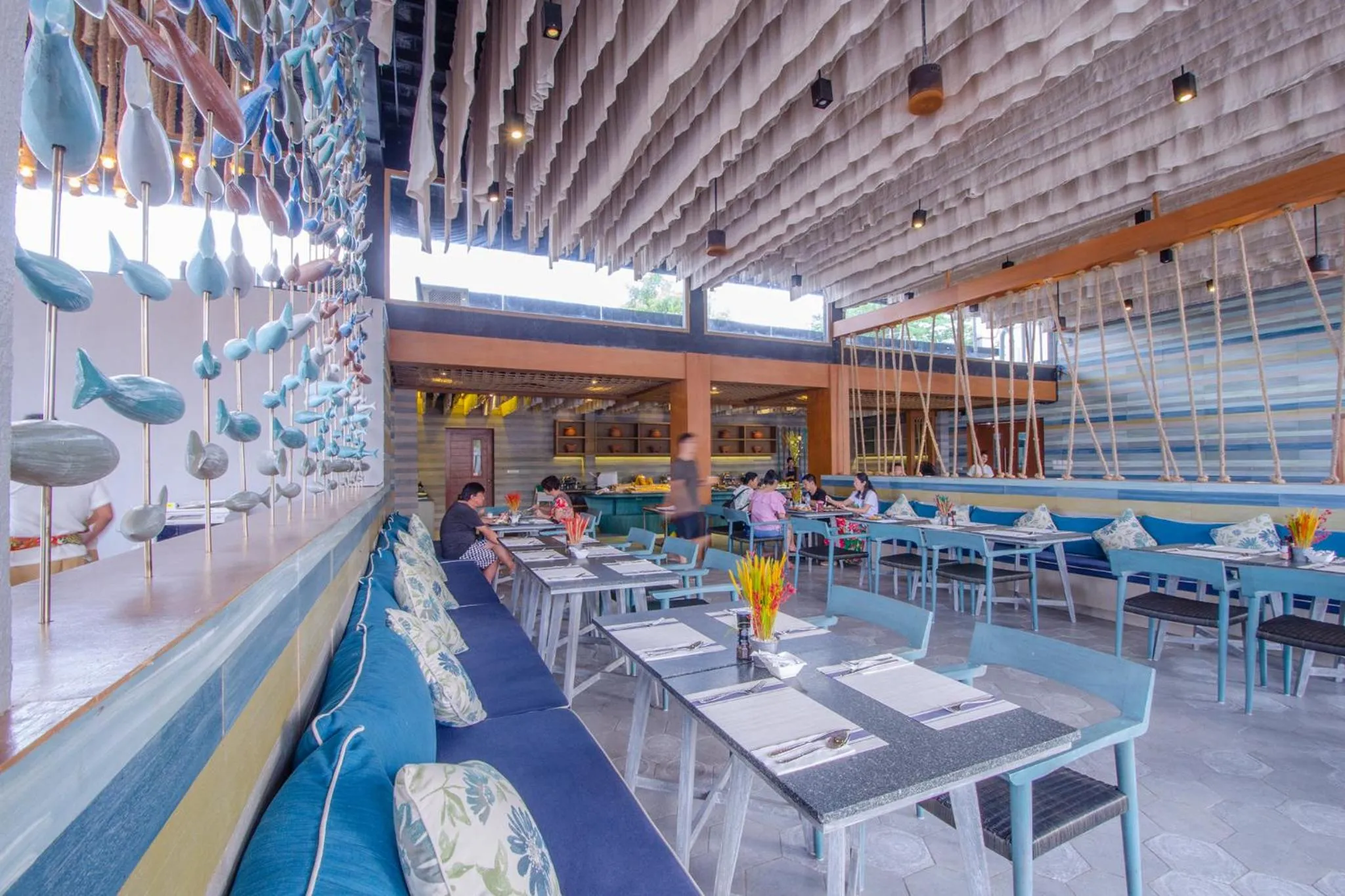 Une salle de restaurant lumineuse avec des tables dressées et des clients attablés.