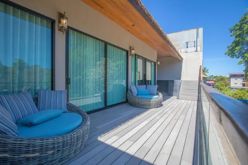 Terrasse aménagée avec des fauteuils en rotin et une vue sur la végétation.