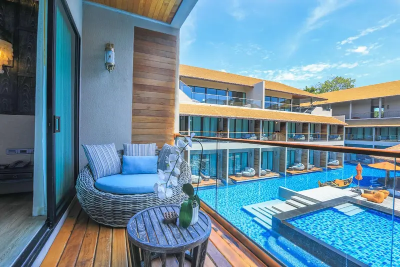 Terrasse aménagée avec salon et vue sur une piscine et des bâtiments.