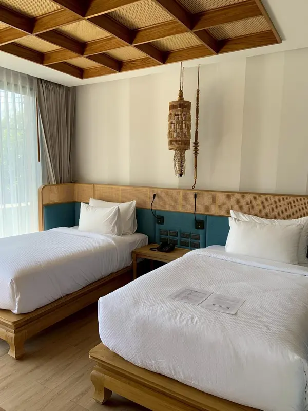 Une chambre lumineuse avec deux lits simples et une décoration en bois et rotin.