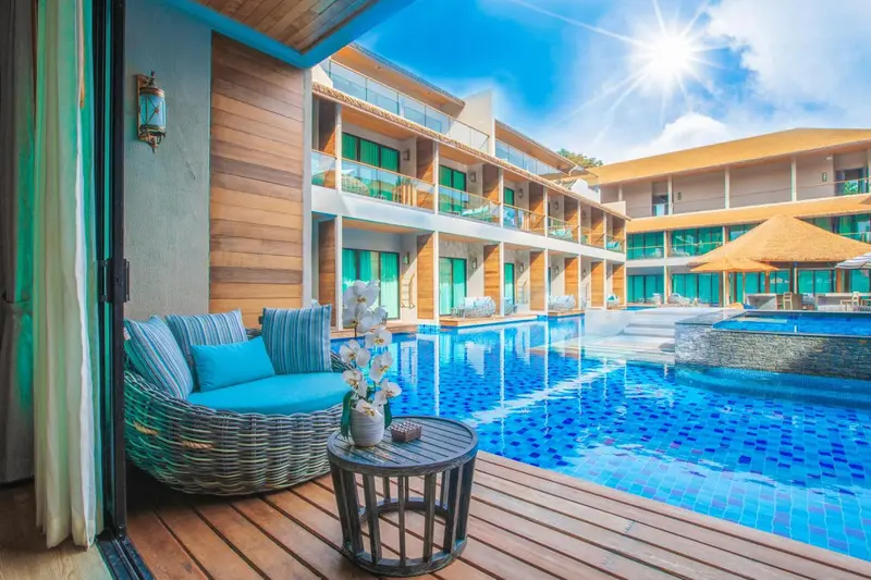 Espace détente avec canapés en rotin et table basse au bord d'une piscine turquoise.