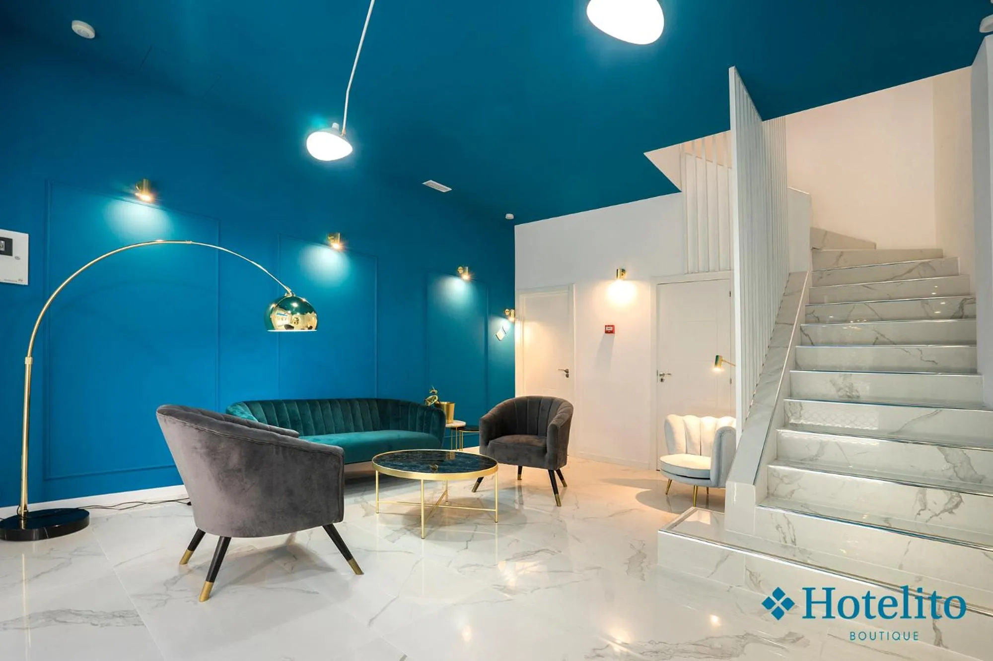 Un espace de détente intérieur avec canapés et fauteuils est éclairé par des lampes sur pied.