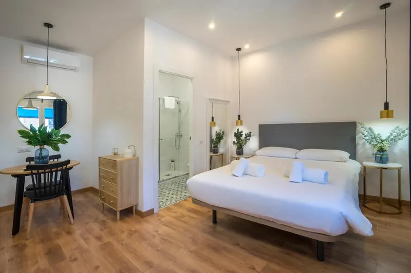Une chambre lumineuse avec un lit double et un coin repas.