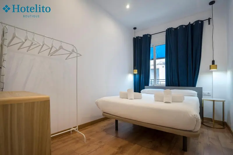 Une chambre lumineuse avec un grand lit et un portant à vêtements.
