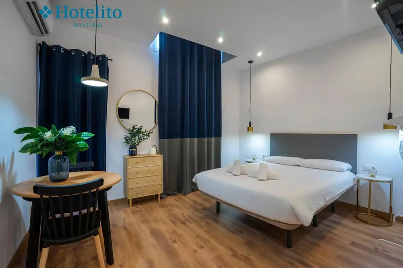 Une chambre lumineuse avec un lit double et une table ronde près de la fenêtre.