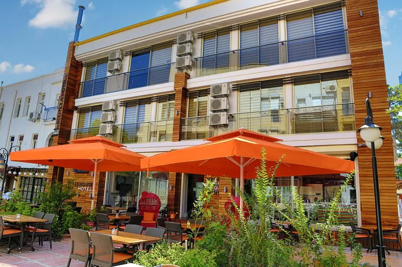Façade d'un bâtiment avec des parasols orange et des tables de terrasse.