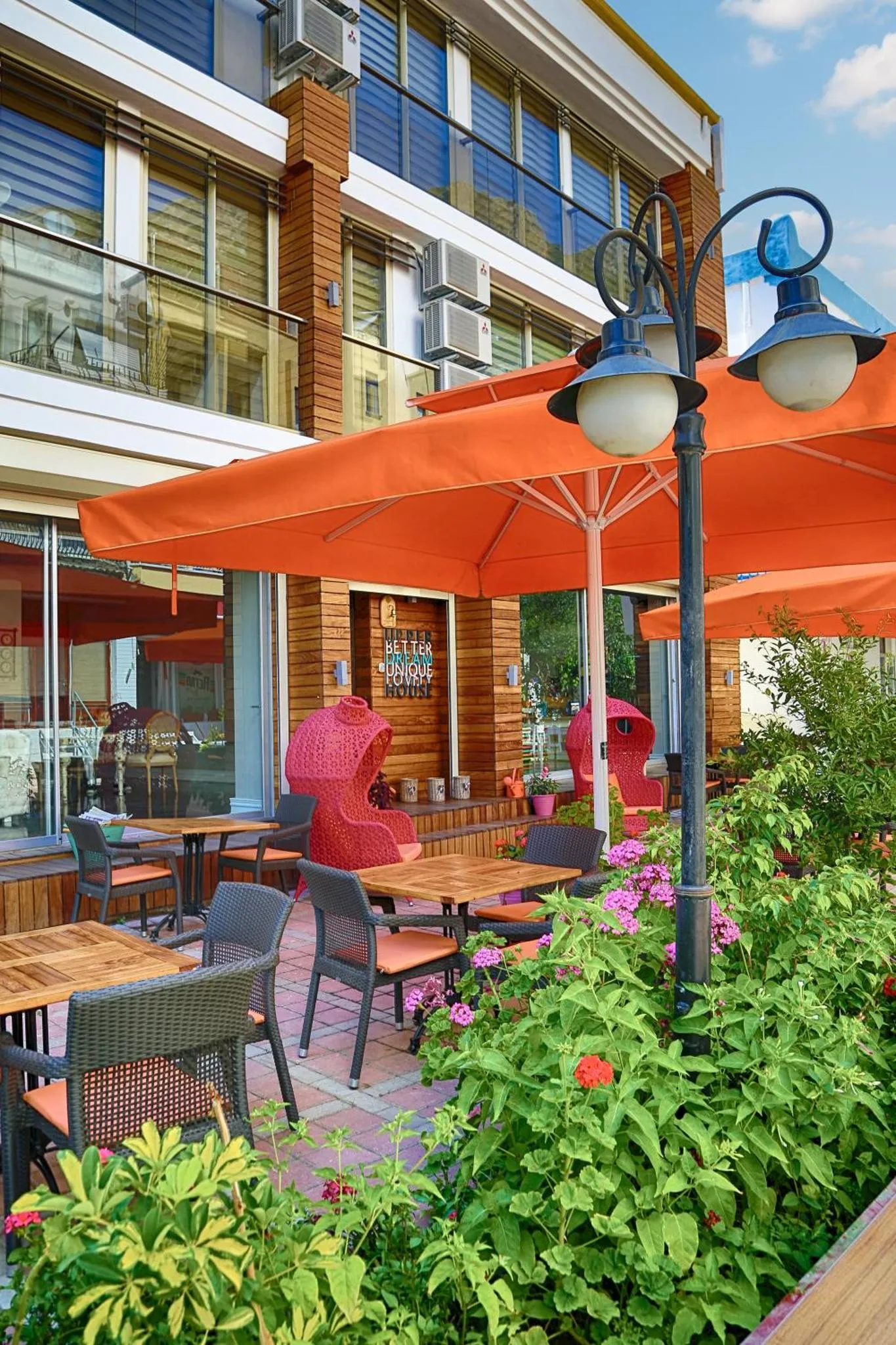 Terrasse ombragée avec tables et chaises au milieu d'une végétation fleurie.