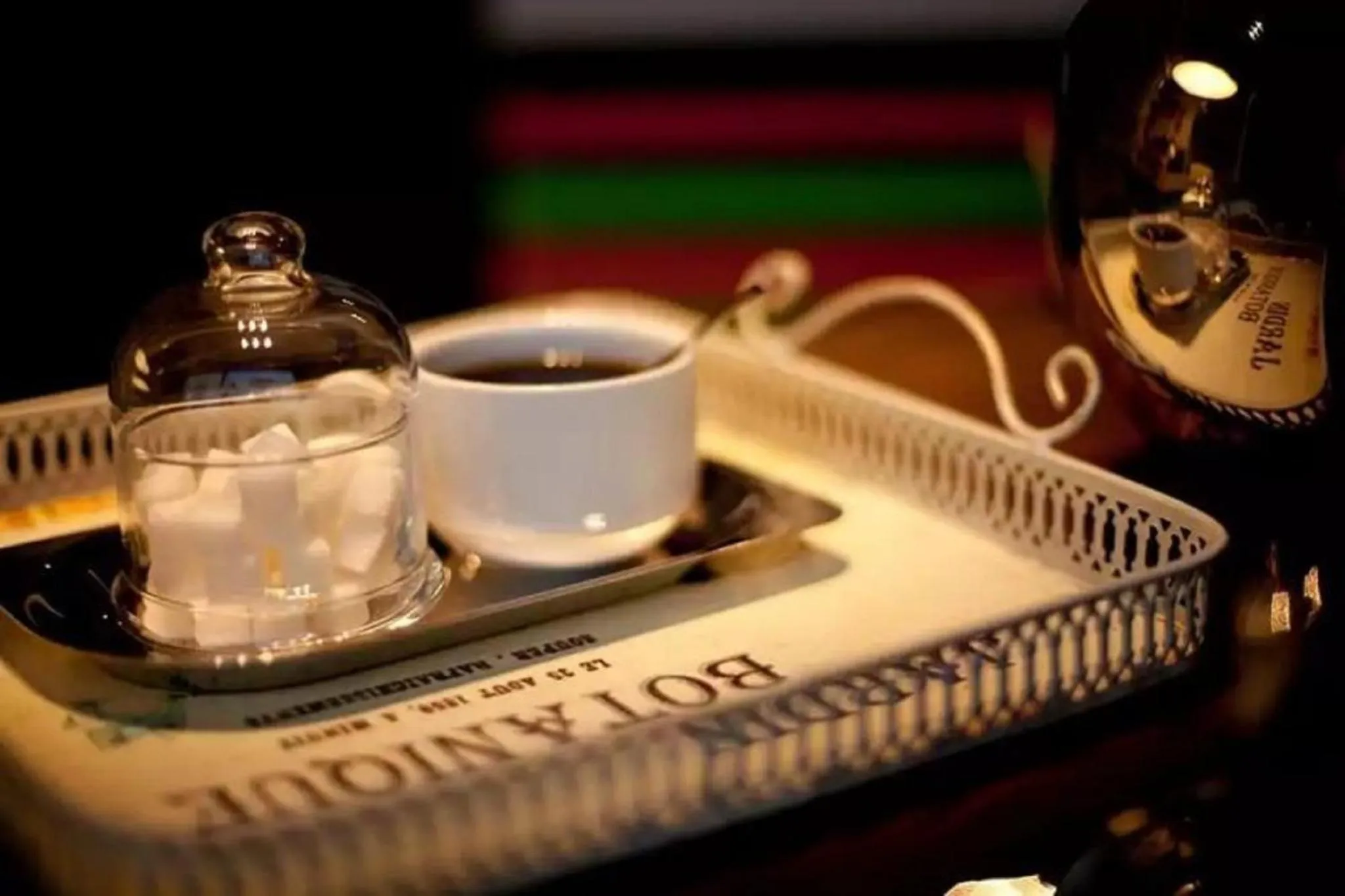 Un plateau en métal ajouré présente une tasse de café, du sucre et une carafe.