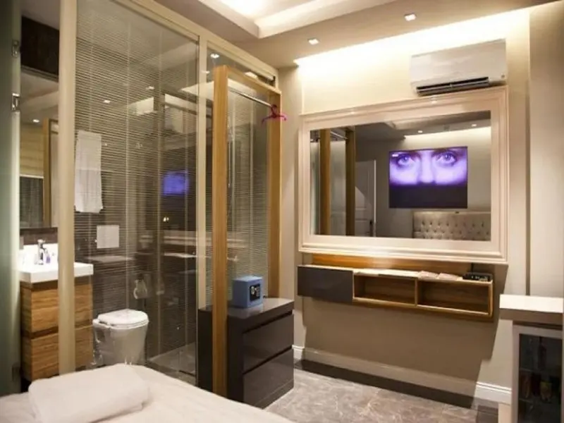 Une salle de bain moderne avec douche à l'italienne et télévision intégrée au miroir.