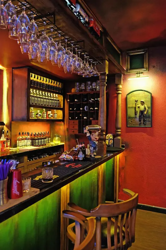 Un comptoir de bar illuminé propose une sélection de boissons et de spiritueux.