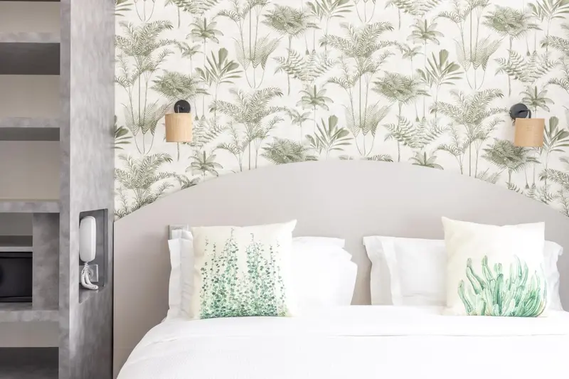 Un lit double avec une tête de lit arrondie dans une chambre décorée de motifs végétaux.