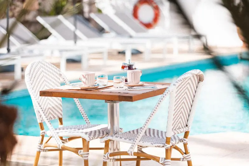 Une table avec des couverts et des boissons est placée près d'une piscine.