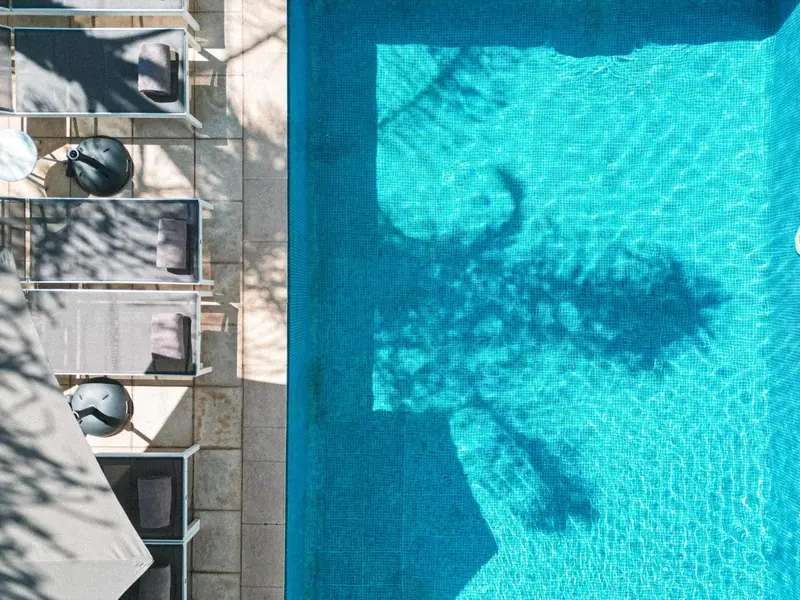 Transats alignés au bord d'une piscine turquoise sous le soleil.