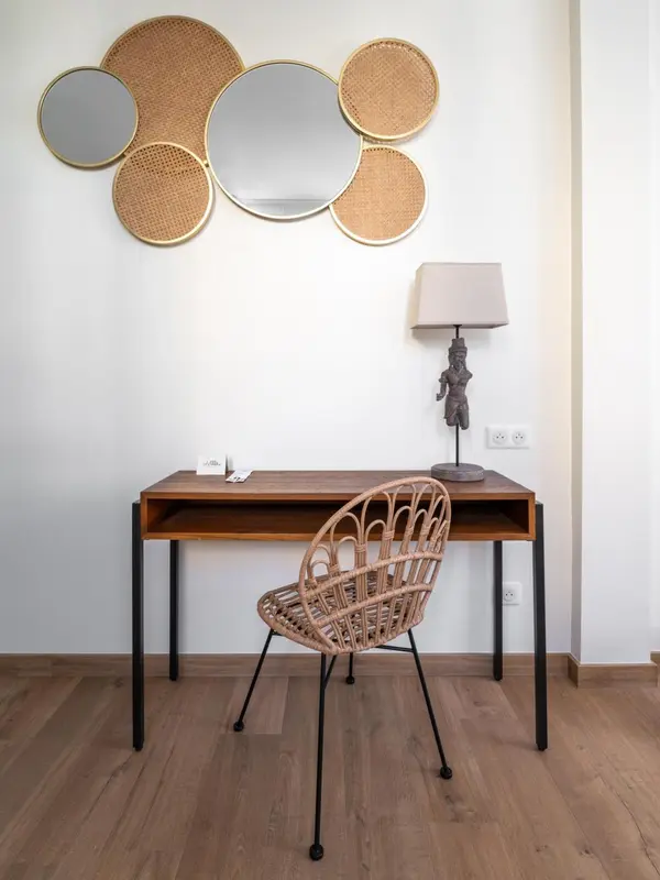 Un bureau en bois avec une chaise en rotin et des miroirs décoratifs sur le mur.