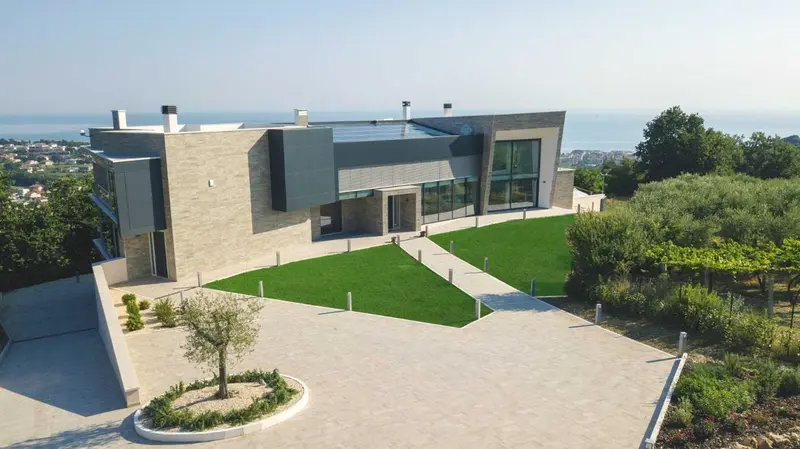 Architecture moderne avec pelouse verdoyante et vue sur la mer.
