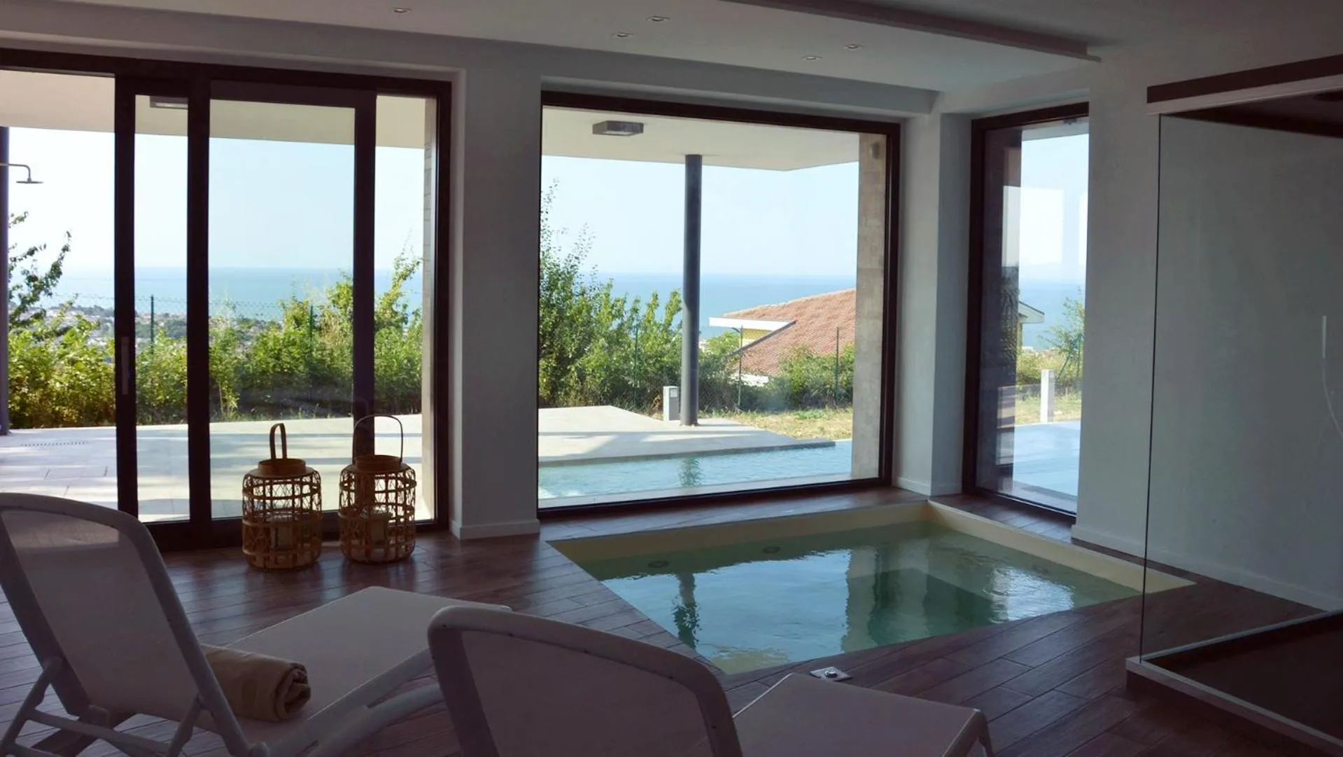 Espace de détente intérieur avec vue sur la mer et piscine.