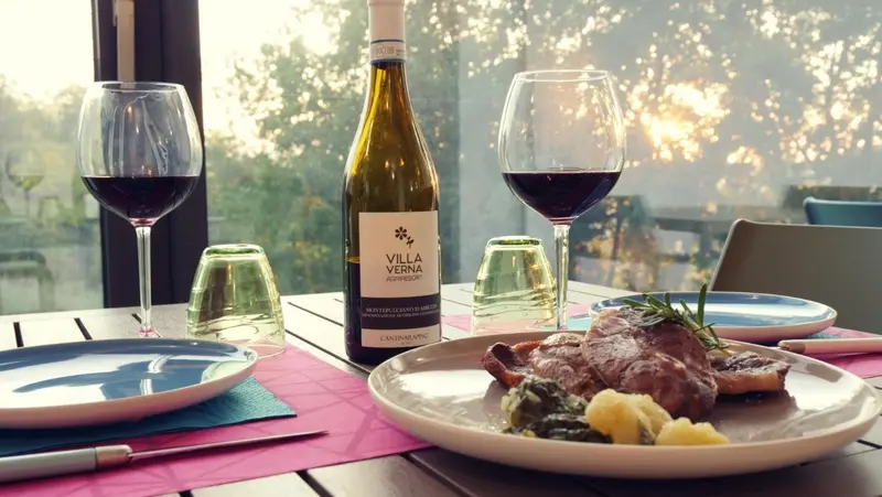 Une table est dressée avec des plats, des verres de vin et de la vaisselle.