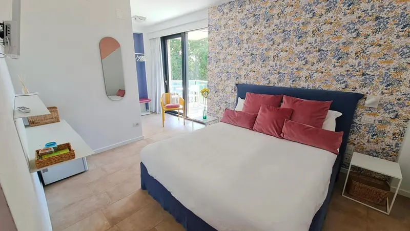 Une chambre lumineuse avec un grand lit et un décor floral.
