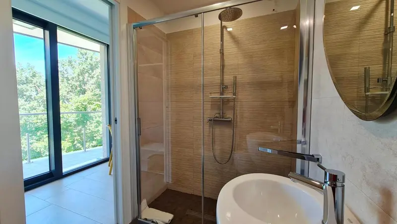 Une douche à l'italienne moderne avec un grand miroir rond.