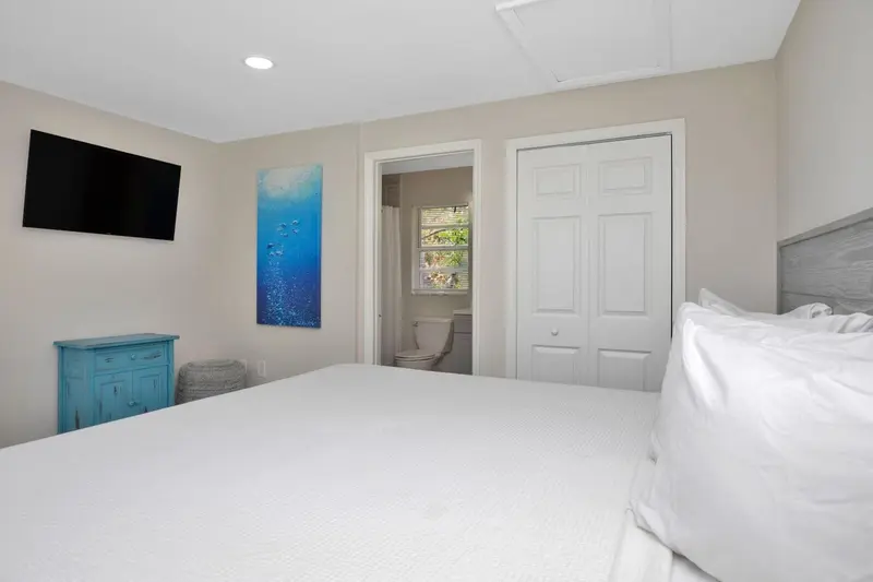 Une chambre lumineuse avec un lit fait et un accès à une salle de bain.