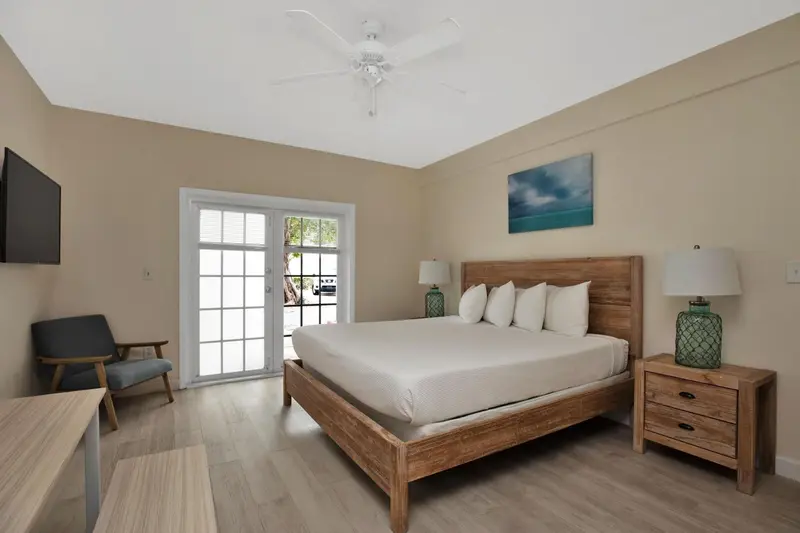 Une chambre lumineuse avec un lit double et un fauteuil.