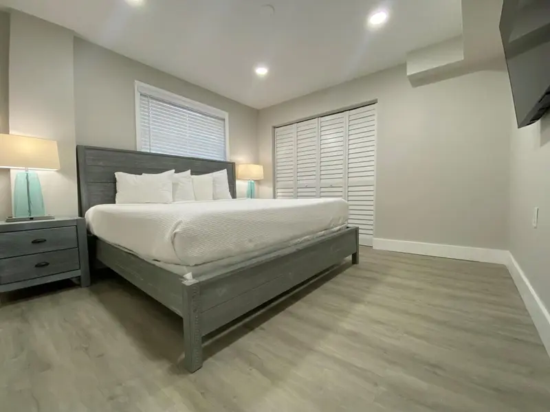 Une chambre lumineuse avec un grand lit et des meubles gris.