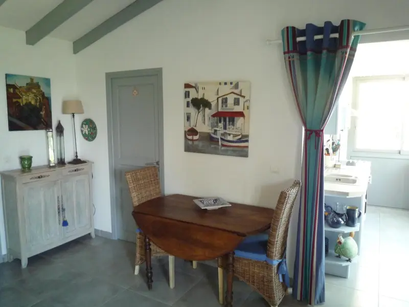 Une salle à manger lumineuse avec une table en bois et des chaises en rotin.