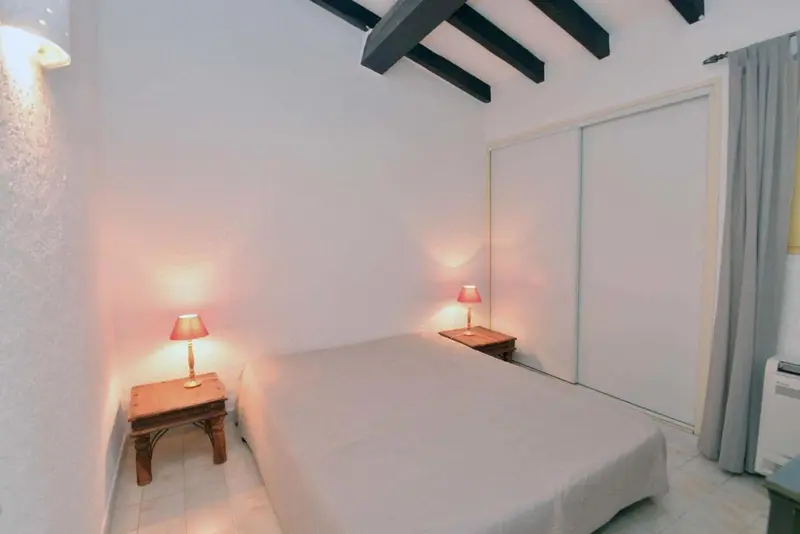 Une chambre lumineuse avec un lit recouvert d'un drap blanc et deux lampes de chevet.