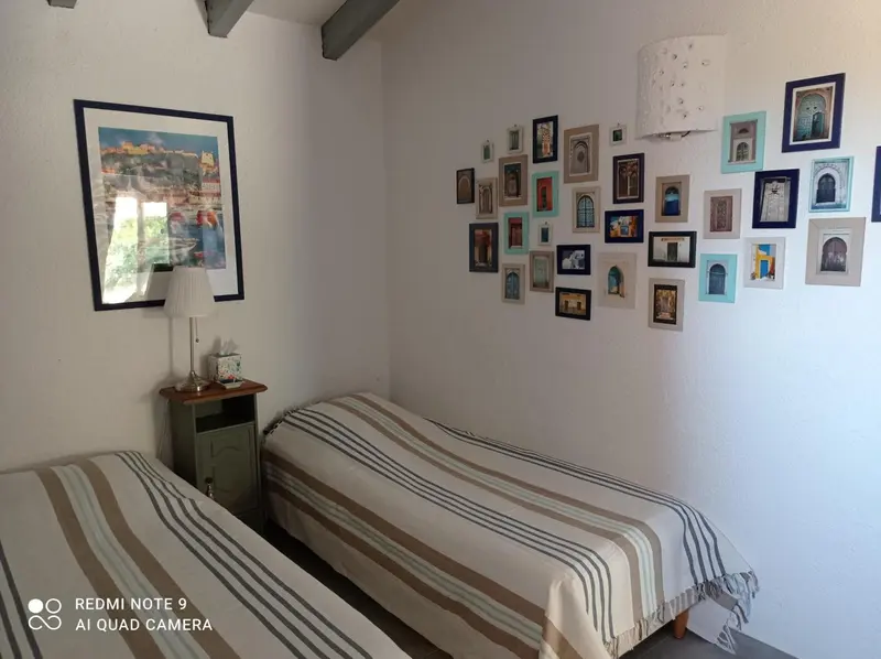Une chambre avec deux lits simples et une décoration murale composée de tableaux.
