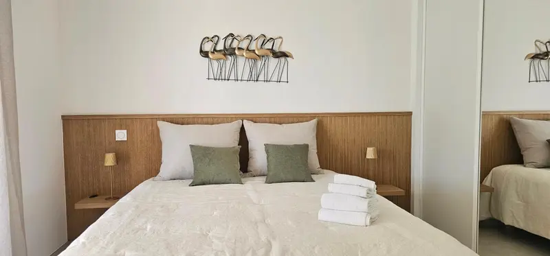 Une chambre lumineuse avec un grand lit recouvert de linge blanc et des oreillers.