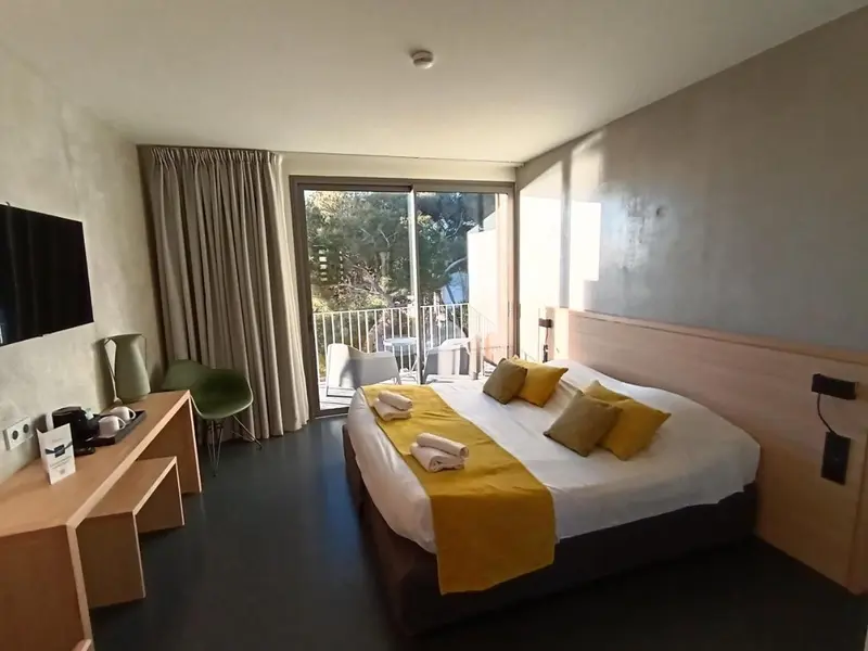 Une chambre lumineuse avec un lit double et un accès à une terrasse.