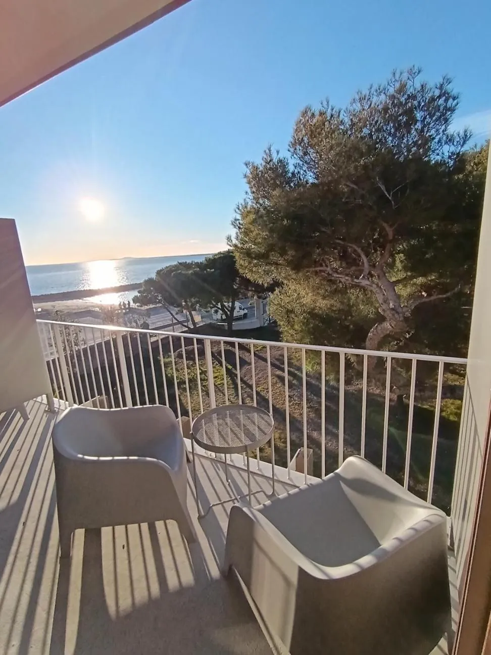 Vue d'une terrasse avec des fauteuils et une table basse donnant sur la mer.