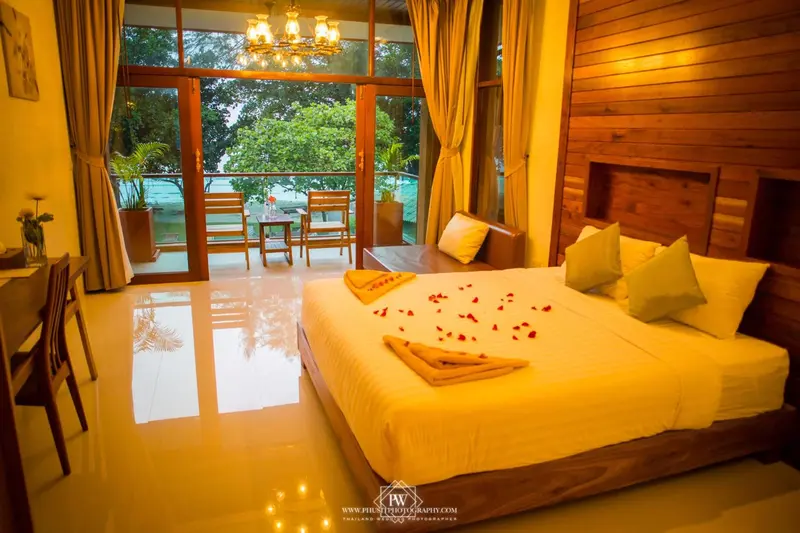 Une chambre lumineuse avec un grand lit et un canapé, donnant sur une terrasse et un paysage verdoyant.