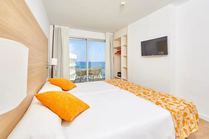 Chambre lumineuse avec un grand lit et vue sur la mer.