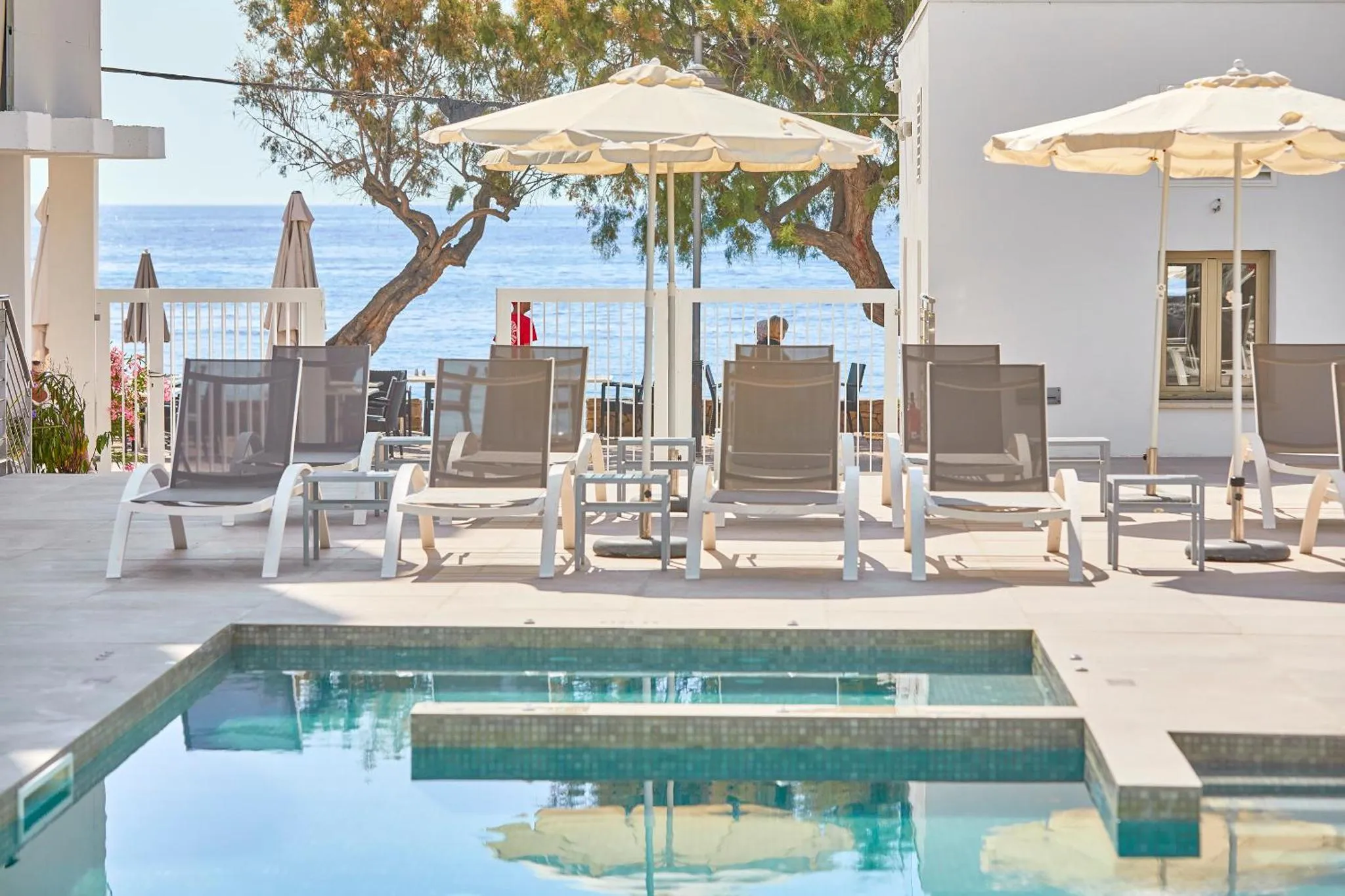 Terrasse avec chaises longues et petite piscine face à la mer.