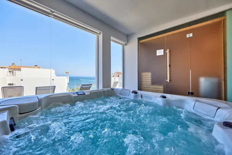 Un jacuzzi intérieur offre une vue dégagée sur la mer et les toits.