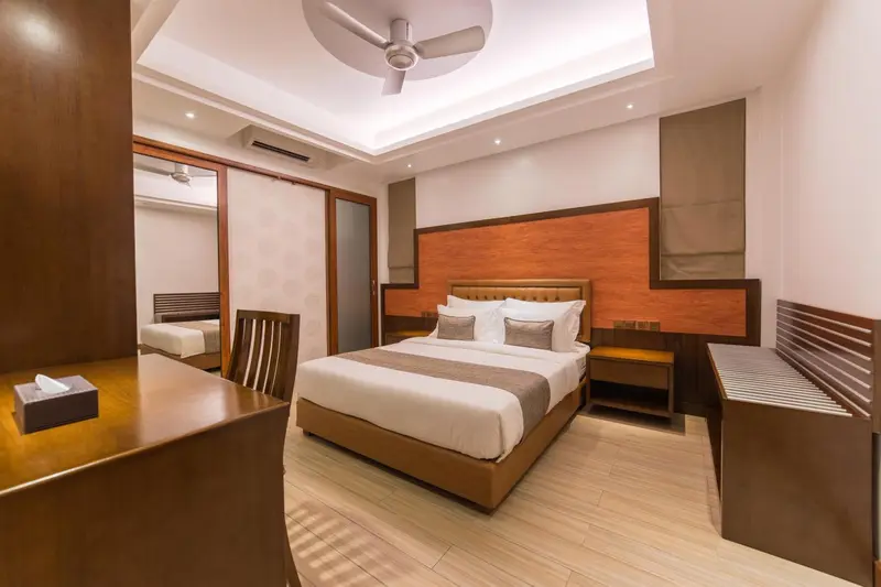Chambre lumineuse avec un grand lit et un bureau en bois.