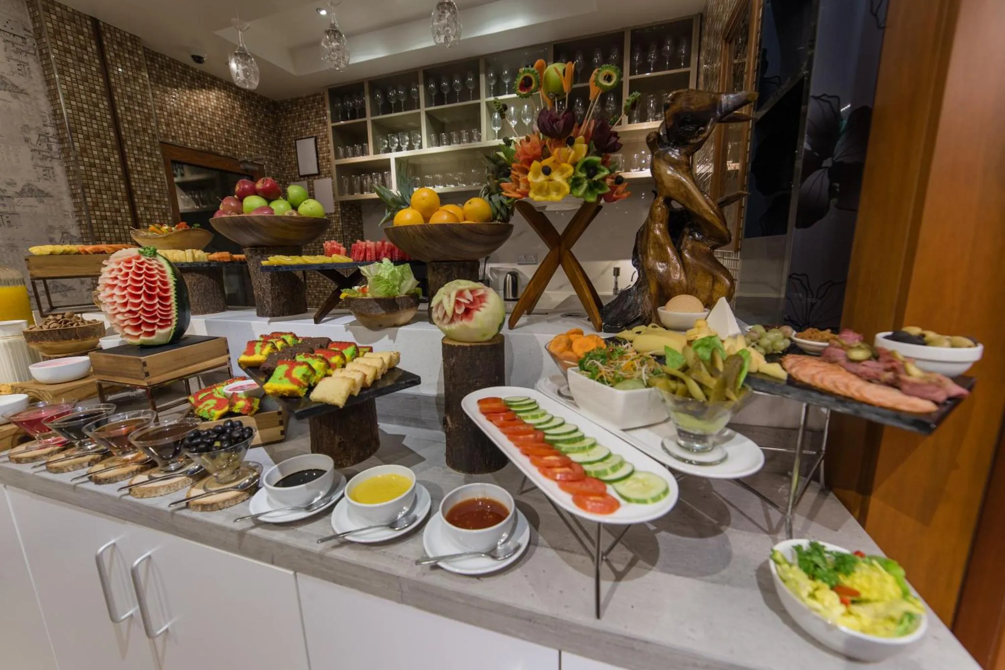 Un buffet propose une variété de fruits frais, de charcuterie et de pâtisseries.