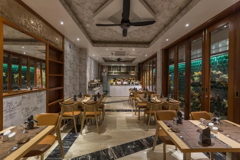 Une salle de restaurant lumineuse avec des tables dressées et une vue sur un jardin.
