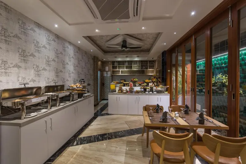 Un buffet de plats variés est présenté dans une salle lumineuse avec des tables dressées.