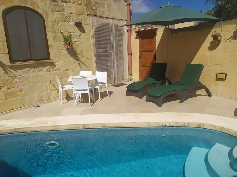 Terrasse avec mobilier de jardin et piscine en contrebas.