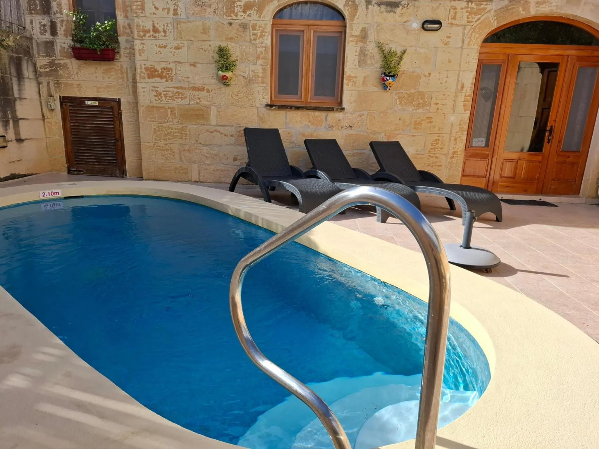 Transats gris disposés au bord d'une piscine bleue en extérieur.