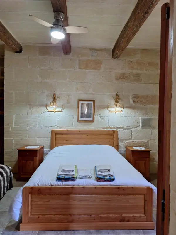 Une chambre lumineuse avec un lit recouvert d'une courtepointe blanche et des tables de chevet en bois.