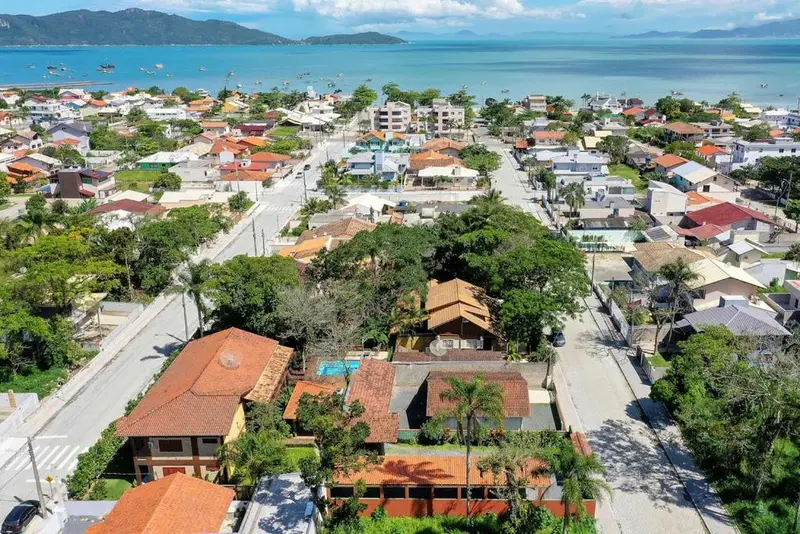 Vue aérienne d'une ville côtière avec des bâtiments aux toits rouges et une plage en arrière-plan.