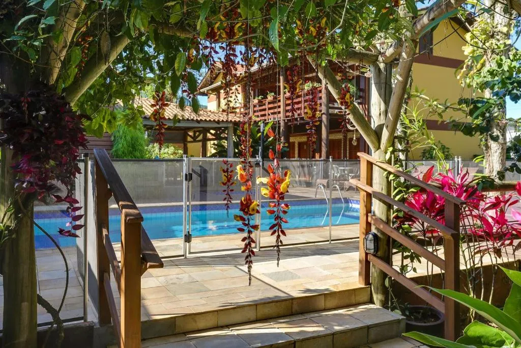 Une piscine rectangulaire bordée d'une terrasse ensoleillée et de végétation luxuriante.