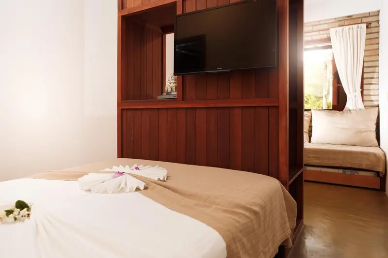 Une chambre avec un lit recouvert de serviettes décorées et un téléviseur mural.